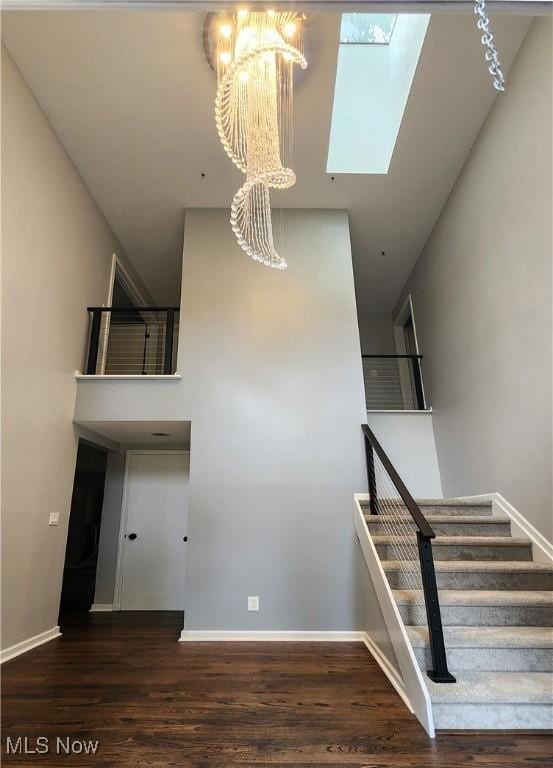 stairway with a skylight, a towering ceiling, and hardwood / wood-style floors