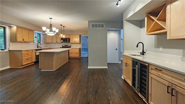 kitchen with appliances with stainless steel finishes, an inviting chandelier, beverage cooler, and dark wood-type flooring