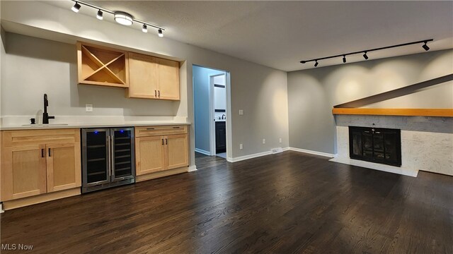 bar with dark wood-type flooring, wine cooler, a fireplace, track lighting, and sink