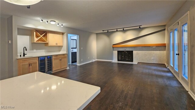 kitchen featuring rail lighting, wine cooler, light brown cabinets, dark hardwood / wood-style floors, and a premium fireplace