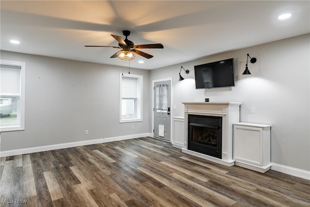 unfurnished living room with ceiling fan and dark wood-type flooring