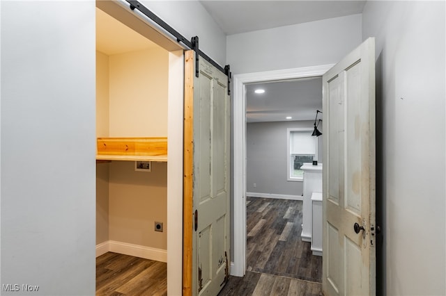 hallway featuring a barn door and dark hardwood / wood-style floors