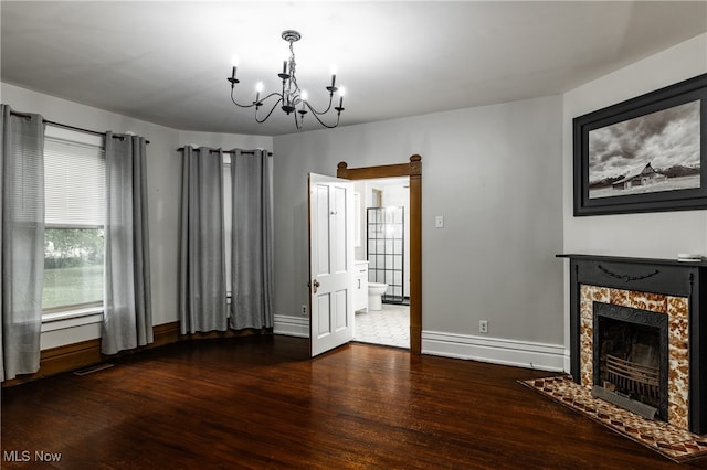 unfurnished living room with an inviting chandelier, a premium fireplace, dark hardwood / wood-style flooring, and a baseboard heating unit