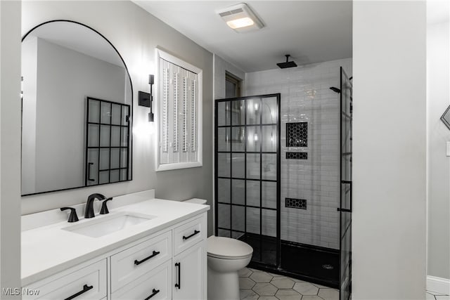 bathroom with tile patterned floors, a shower with door, vanity, and toilet