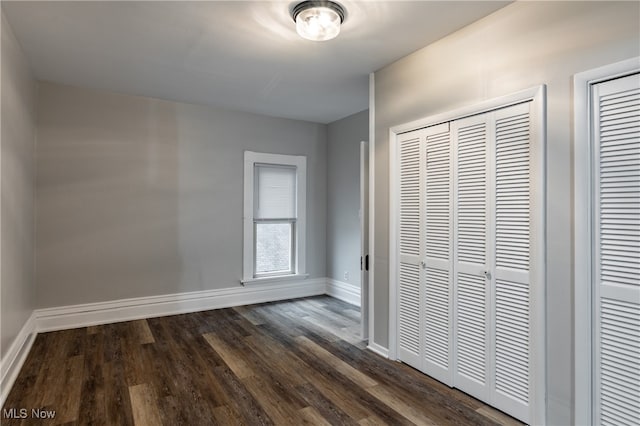 unfurnished bedroom with dark hardwood / wood-style floors and multiple closets