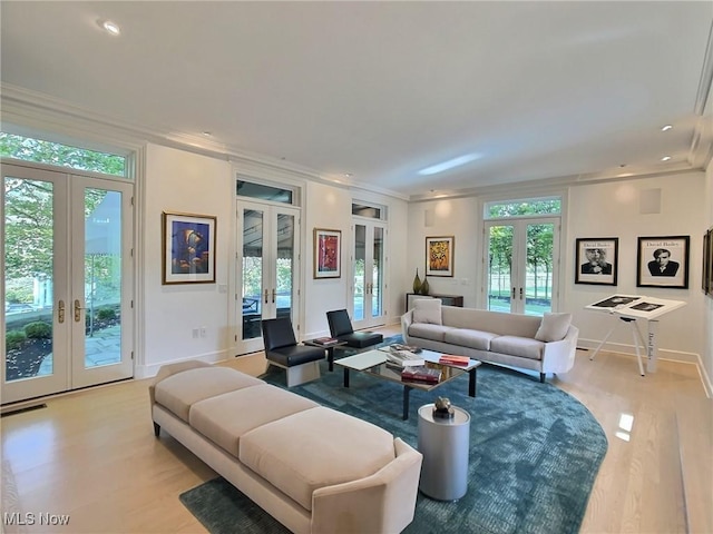 living room with a healthy amount of sunlight, light hardwood / wood-style flooring, french doors, and crown molding