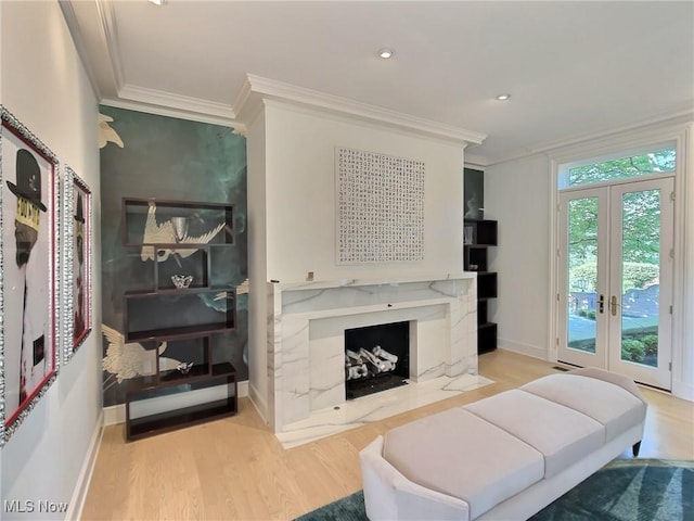 living room with french doors, a fireplace, light wood-type flooring, and crown molding