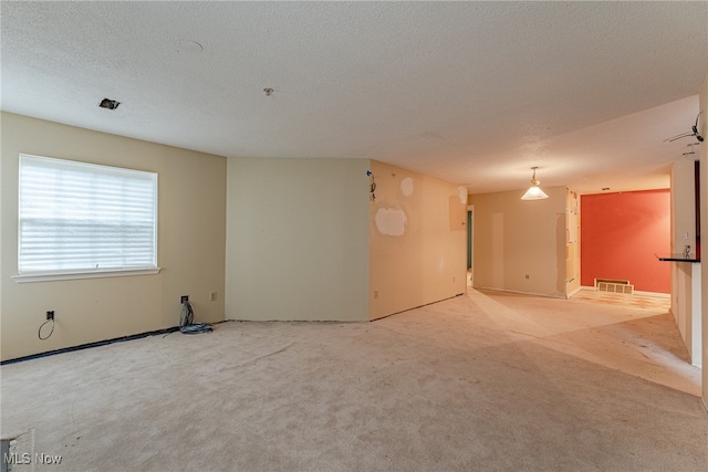 carpeted empty room featuring a textured ceiling