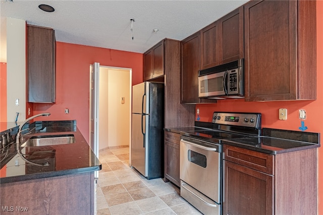 kitchen with a textured ceiling, dark brown cabinets, sink, and stainless steel appliances