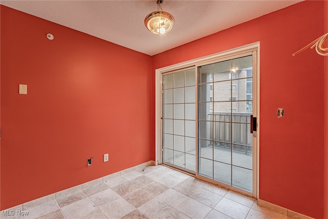 tiled empty room featuring a textured ceiling