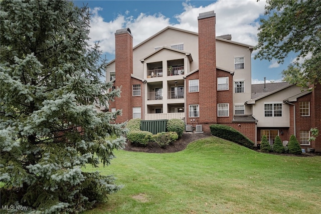 rear view of property with a lawn, a balcony, and central AC unit