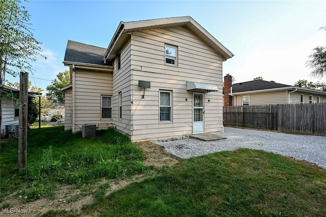 back of house with a yard and central AC