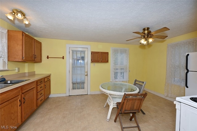 kitchen featuring ceiling fan, a textured ceiling, sink, and white appliances