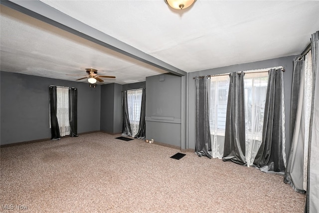 carpeted spare room featuring ceiling fan and plenty of natural light