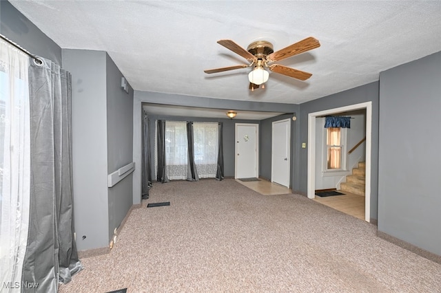 carpeted empty room featuring a textured ceiling, a healthy amount of sunlight, and ceiling fan