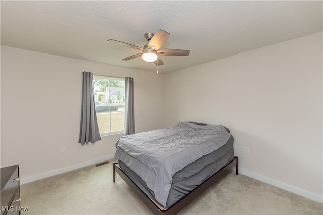 bedroom featuring a textured ceiling, light carpet, and ceiling fan