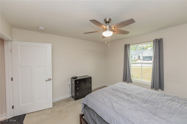 carpeted bedroom featuring ceiling fan and a textured ceiling