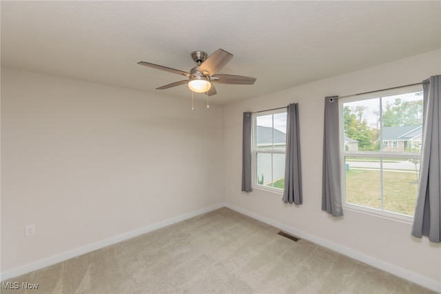 carpeted spare room with a wealth of natural light, ceiling fan, and a textured ceiling