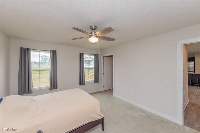 bedroom featuring a textured ceiling, light carpet, and ceiling fan