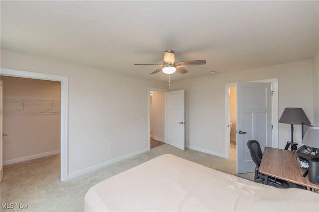 bedroom with light carpet, ceiling fan, a walk in closet, and a closet