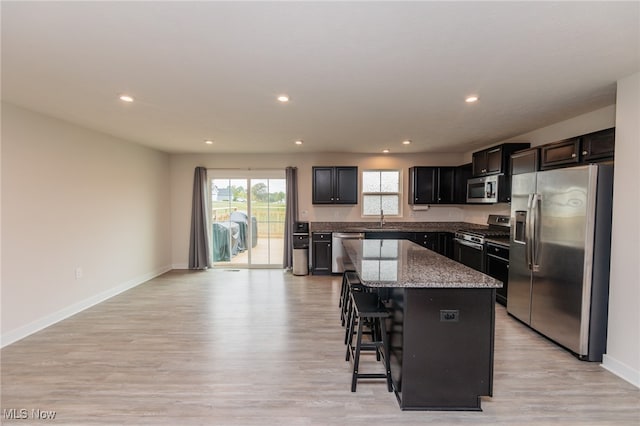 kitchen featuring sink, stainless steel appliances, a kitchen breakfast bar, a center island, and light hardwood / wood-style floors