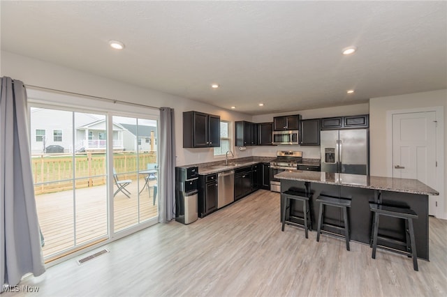 kitchen with a center island, a breakfast bar area, sink, light hardwood / wood-style flooring, and stainless steel appliances