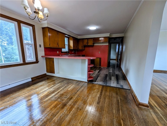 kitchen with crown molding, kitchen peninsula, dark hardwood / wood-style floors, and a notable chandelier