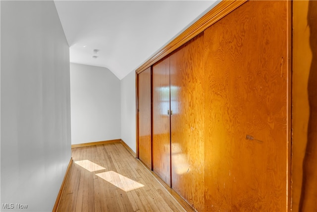 hall with light hardwood / wood-style flooring and vaulted ceiling