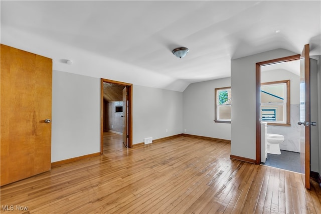 empty room featuring vaulted ceiling and light hardwood / wood-style flooring