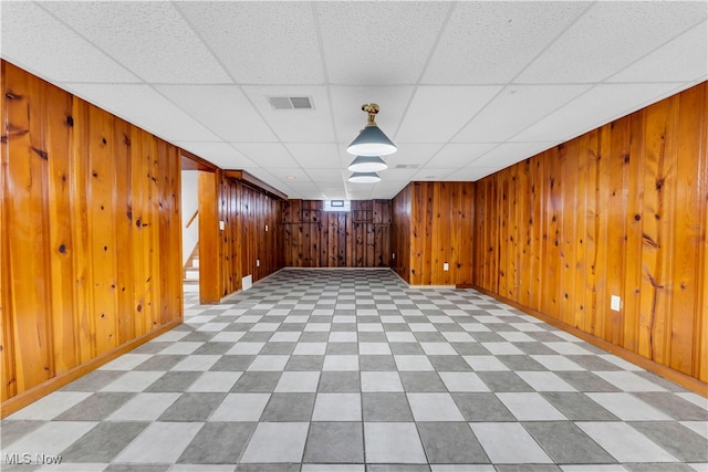 basement with wooden walls and a drop ceiling