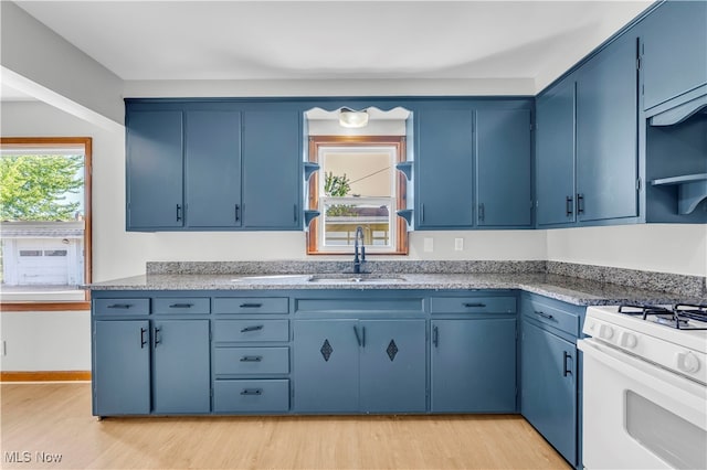 kitchen with blue cabinets, light hardwood / wood-style flooring, sink, and white gas range oven