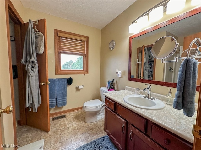 bathroom featuring vanity, toilet, and a textured ceiling