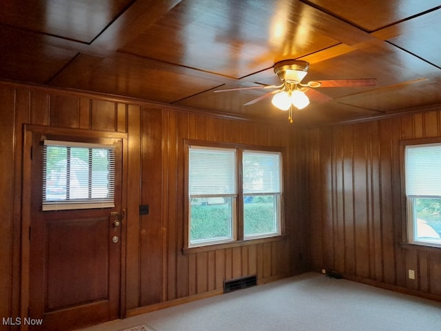 carpeted entryway featuring wood walls, ceiling fan, wooden ceiling, and a healthy amount of sunlight