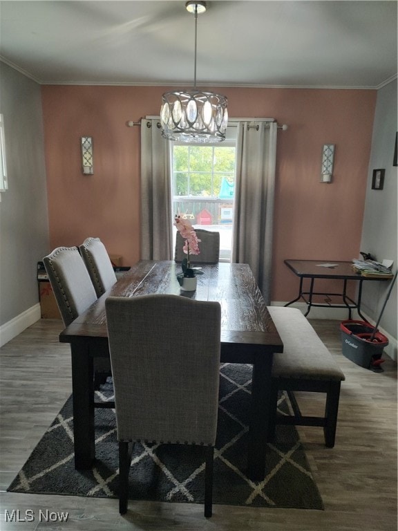 dining area with a notable chandelier, ornamental molding, and hardwood / wood-style flooring