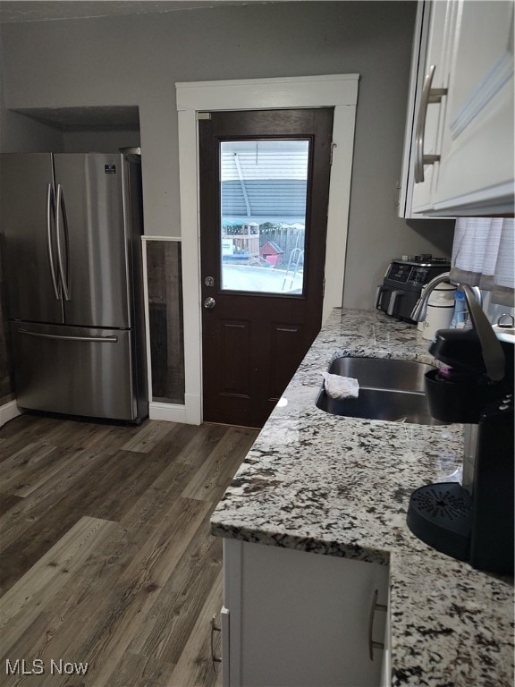 kitchen featuring stainless steel refrigerator, white cabinetry, dark wood-type flooring, and light stone counters