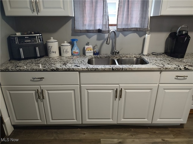 kitchen featuring light stone counters, white cabinets, dark hardwood / wood-style floors, and sink