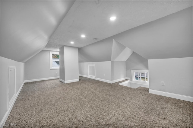 bonus room with a textured ceiling, vaulted ceiling, and carpet