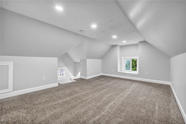 additional living space featuring vaulted ceiling and carpet flooring