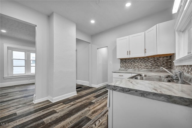 kitchen with white cabinets, dark wood-type flooring, sink, and tasteful backsplash