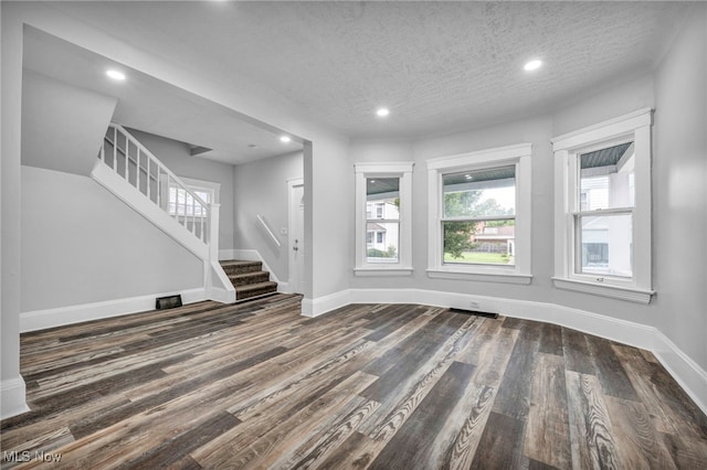 unfurnished living room with a textured ceiling and dark hardwood / wood-style flooring