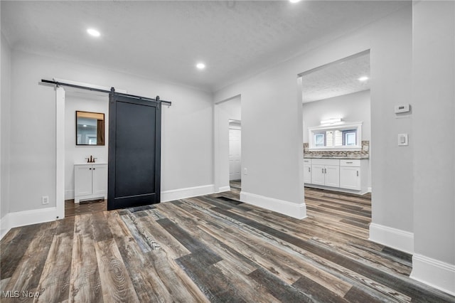 unfurnished living room featuring a textured ceiling, dark hardwood / wood-style floors, and a barn door