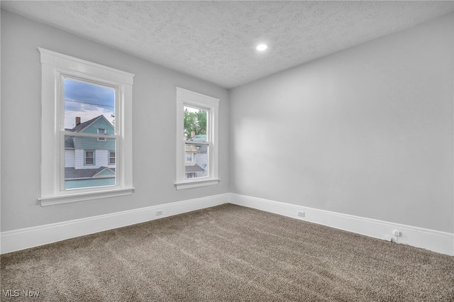 carpeted empty room featuring a textured ceiling