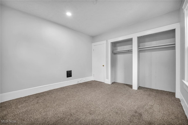 unfurnished bedroom featuring carpet and multiple closets