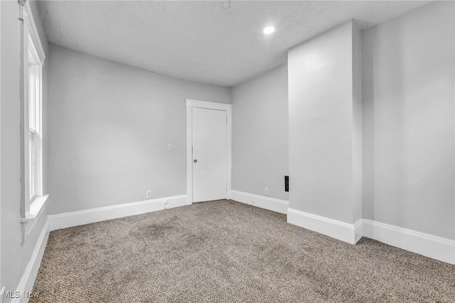 carpeted spare room featuring a textured ceiling