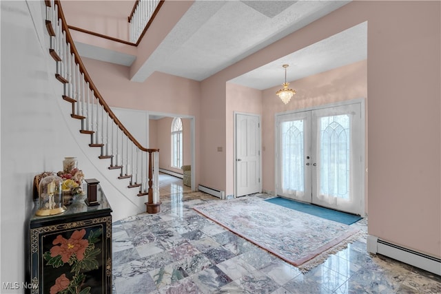 foyer entrance featuring a healthy amount of sunlight, baseboard heating, and french doors