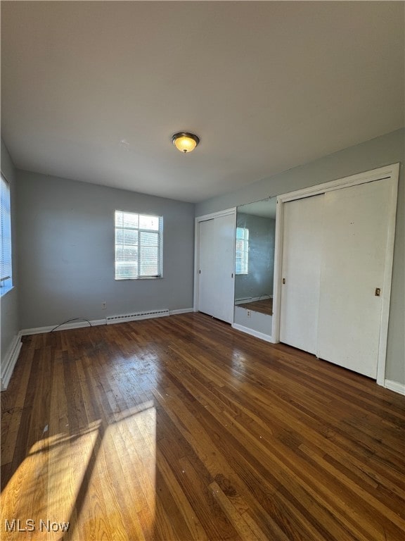 unfurnished bedroom with dark wood-type flooring and a baseboard radiator