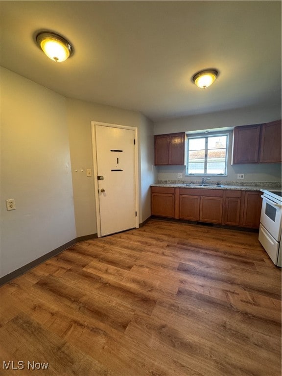 kitchen featuring wood-type flooring, white electric range oven, and sink