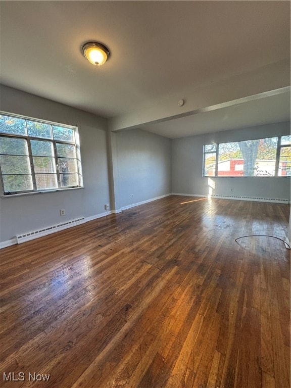 empty room with a baseboard heating unit and dark hardwood / wood-style flooring