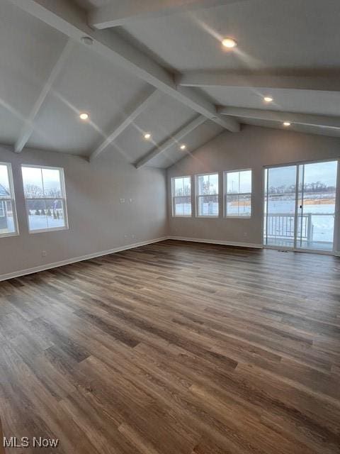 unfurnished room featuring lofted ceiling with beams, a healthy amount of sunlight, and dark wood-type flooring