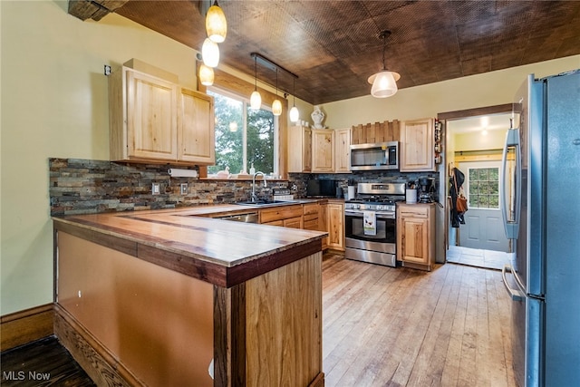 kitchen featuring pendant lighting, stainless steel appliances, a wealth of natural light, and light wood-type flooring